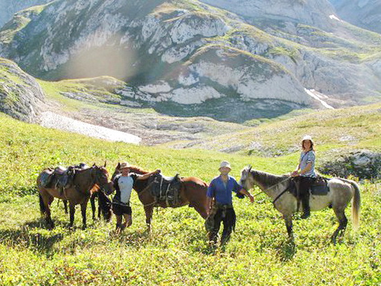 Конный тур на гору Фишт, в Адыгее. Трое всадников на фоне горных хребтов.