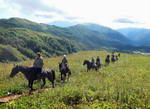 На Кавказе, в Адыгее, во время конного тура. Люди и кони на фоне гор Фишта.
